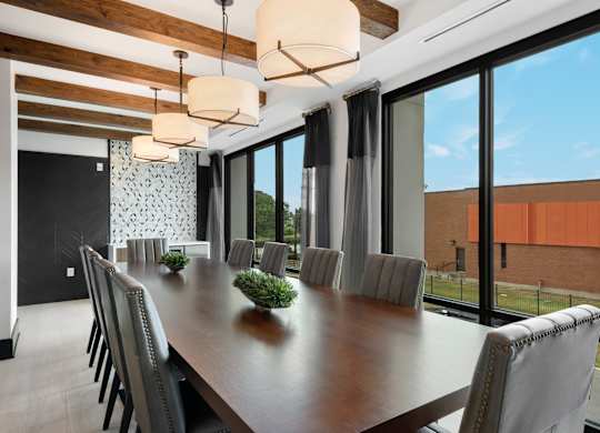 a long table with chairs in a room with large windows