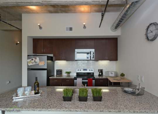 Modern kitchen with granite countertops and dark wood cabinets at 1221 Broadway Lofts Apartments, Texas