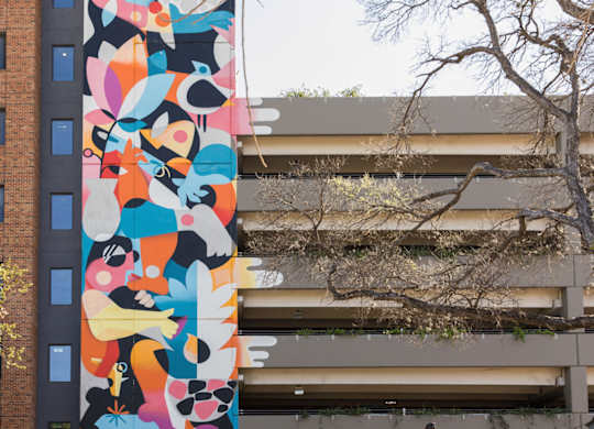 Outdoor courtyard with colorful mural and dining area at THE'68 Apartments, Texas