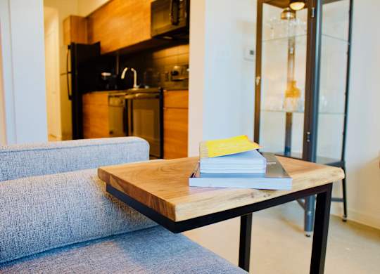 A grey couch sits in front of a wooden coffee table with a book on it.
