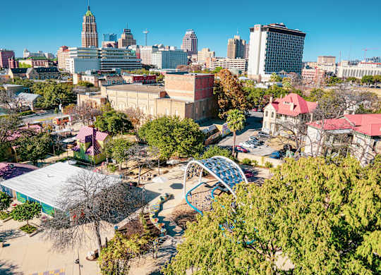 A cityscape with a playground in the foreground.