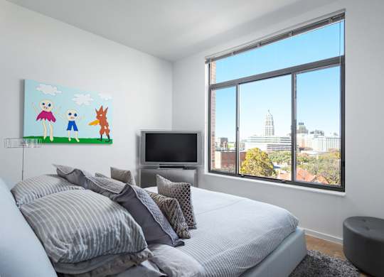 Bedroom with large window and city skyline views at THE'68 Apartments, San Antonio, TX