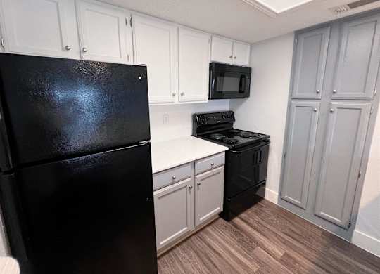 a kitchen with black appliances and white cabinets at Northchase, Austin, TX