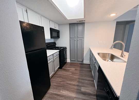 a kitchen with white cabinets and black appliances at Northchase, Austin, TX
