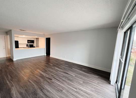 an empty living room with wood flooring and a kitchen at Northchase, Texas, 78753