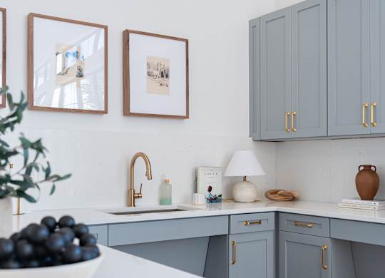 A kitchen with grey cabinets and a white countertop.