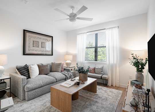 A living room with a grey couch, a wooden coffee table, and a ceiling fan.