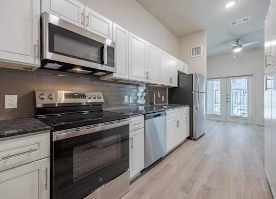 Kitchen with white cabinets and gray countertops at Emilia Apartments, Texas, 78006