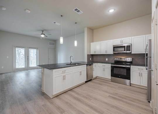 Open concept kitchen with white cabinetry at Emilia Apartments, Boerne, TX 78006