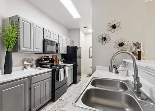 A modern kitchen with a black refrigerator and stove, and a stainless steel sink.