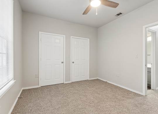 A room with a ceiling fan and three doors.