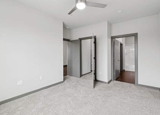 A room with a ceiling fan and carpeted floor.