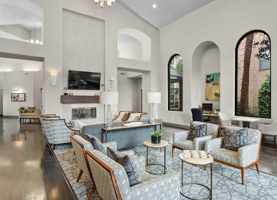 Clubhouse lounge with tall arched windows and seating at Melia Medical Center Apartments, Texas