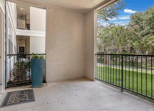 A balcony with a black railing and a green trash can.
