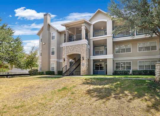 A large two-story apartment building with a stone staircase leading to the entrance.