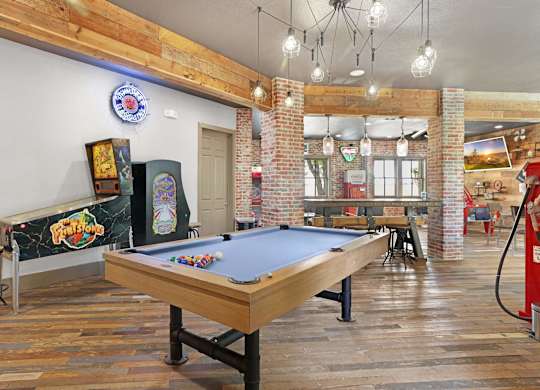 A pool table in a room with a brick wall and a bar.