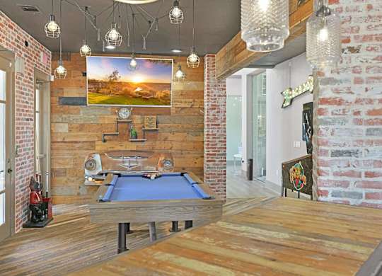 A room with a pool table and a brick wall.