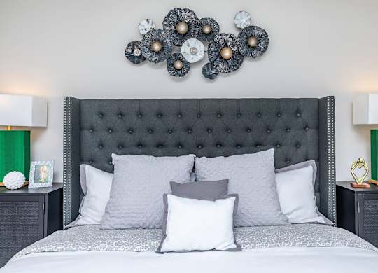 Upholstered tufted bed with decorative wall art at Sienna at Westover Hills Apartments, San Antonio