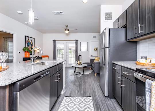 Galley kitchen with dark cabinets and granite counters at Sienna at Westover Hills Apartments, San Antonio, Texas
