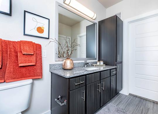 Bathroom vanity with dark wood cabinets and granite top at Sienna at Westover Hills Apartments, San Antonio, Texas