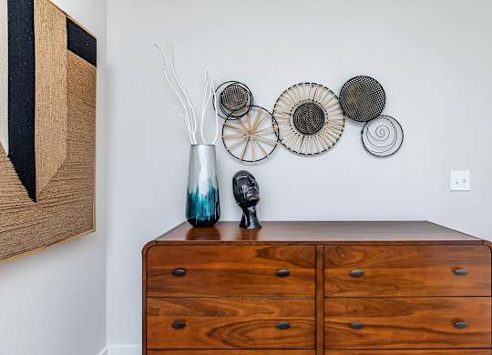 Wooden dresser with decorative vase and wall art at Sienna at Westover Hills Apartments, Texas, 78253