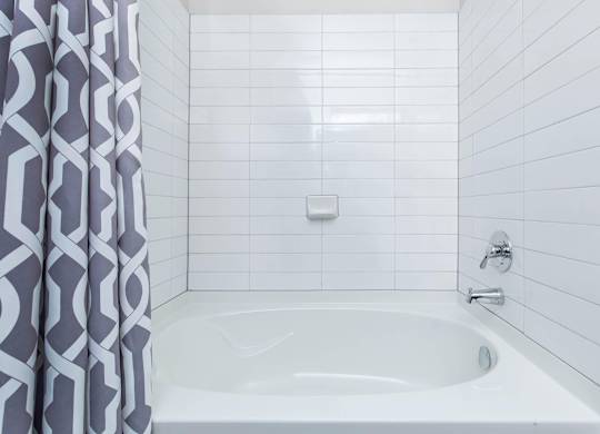 White tiled bathtub with patterned shower curtain at Sienna at Westover Hills Apartments, Texas, 78253