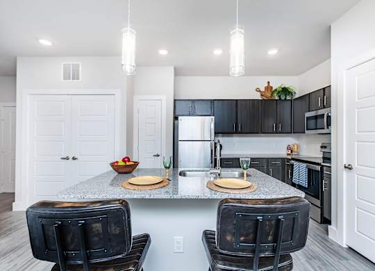 Kitchen island with pendant lights and dark cabinetry at Sienna at Westover Hills Apartments, Texas, 78253