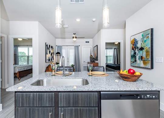 Kitchen island with granite countertop and stainless steel sink at Sienna at Westover Hills Apartments, San Antonio, Texas