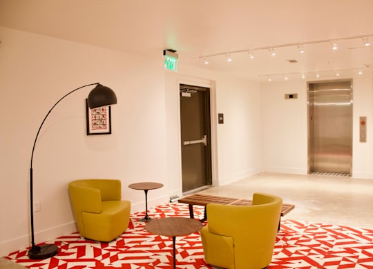 Lobby seating area with yellow chairs and floor lamp at THE'68 Apartments, San Antonio, TX 78205