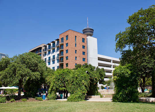 Apartment building exterior with park and trees at THE'68 Apartments, San Antonio