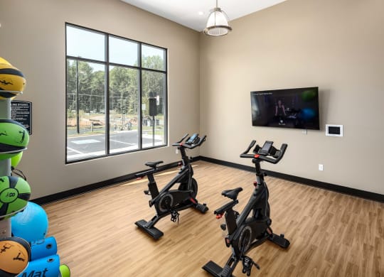 an exercise room with two treadmills and a flat screen tv