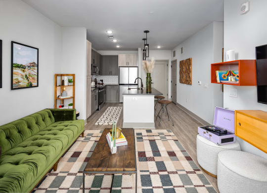 a living room with a green couch and a kitchen in the backgroundat Abberly Foundry Apartment Homes, Nashville, TN, 37206