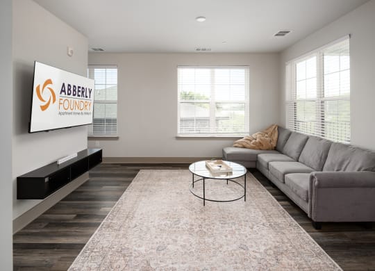 a living room with a couch and coffee table in front of a flat screen tv at Abberly Foundry Apartment Homes, Nashville, TN, 37203