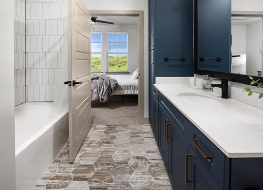 a bathroom with blue cabinets and a white bathtub at Abberly Foundry Apartment Homes, Nashville, Tennessee