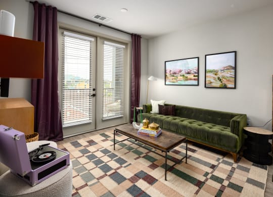 a living room with a green couch and purple curtains at Abberly Foundry Apartment Homes, Nashville