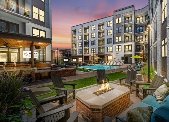 an outdoor lounge area with a fire pit and lounge chairs with a pool in the backgroundat Abberly Foundry Apartment Homes, Nashville, TN