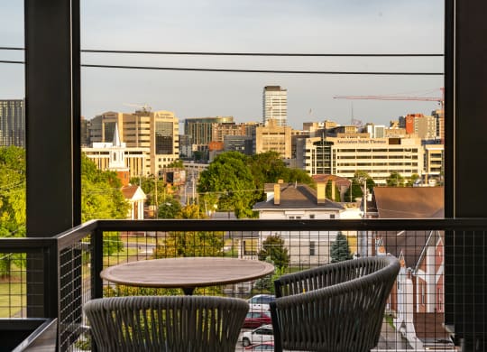 a balcony with two chairs and a table with a view of the city at Abberly Foundry Apartment Homes, Nashville
