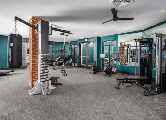 a gym with a lot of exercise equipment and a brick column in the middle of the room at Abberly Foundry Apartment Homes, Nashville