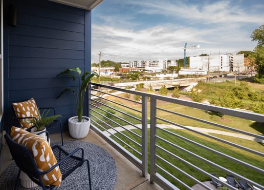 a balcony with a chair and a potted plant and a view of the city  at Abberly Noda Vista Apartment Homes, Charlotte, NC
