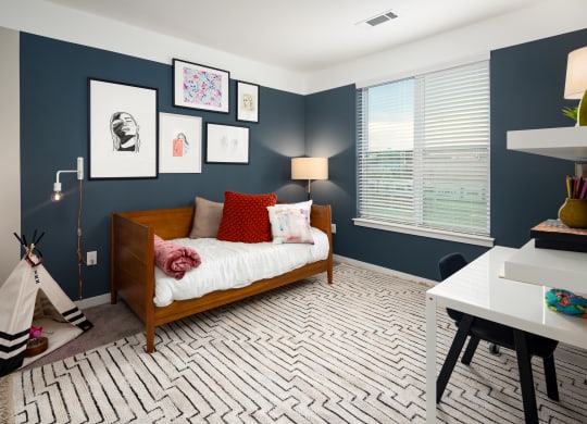 a bedroom with navy blue walls and a white bedspread with red pillows at Abberly Noda Vista Apartment Homes, North Carolina
