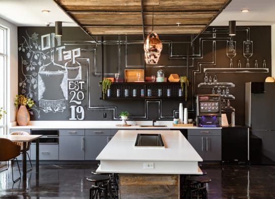 a kitchen with a large white island in front of a chalkboard wall at Abberly Noda Vista Apartment Homes, North Carolina, 28206