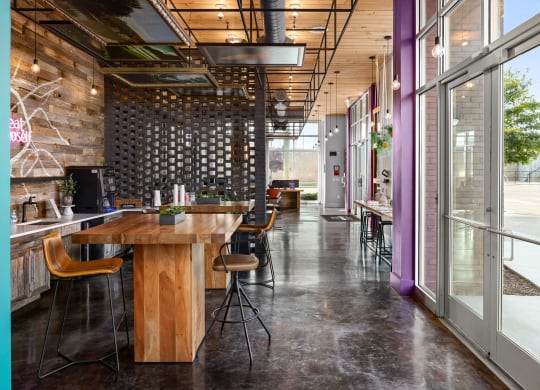 a large wooden table with chairs in a room with glass doors and windows  at Abberly Noda Vista Apartment Homes, North Carolina