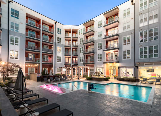 an apartment complex with a swimming pool and lounge chairs  at Abberly Noda Vista Apartment Homes, North Carolina, 28206
