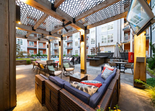 an outdoor patio with wicker furniture and a pergola  at Abberly Noda Vista Apartment Homes, Charlotte