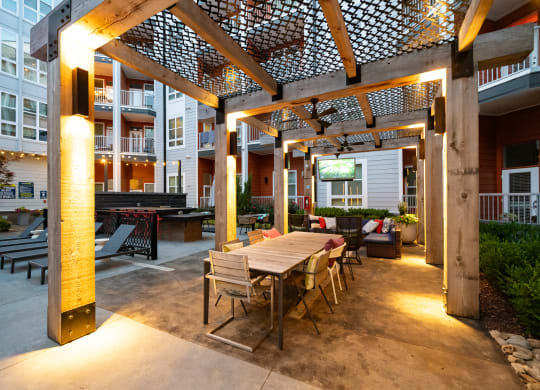 a patio with a wooden table and chairs and a pergola over it  at Abberly Noda Vista Apartment Homes, Charlotte, NC