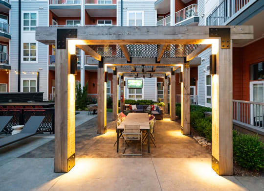 an outdoor dining area with a wooden table and chairs under a wooden pergola  at Abberly Noda Vista Apartment Homes, Charlotte, NC