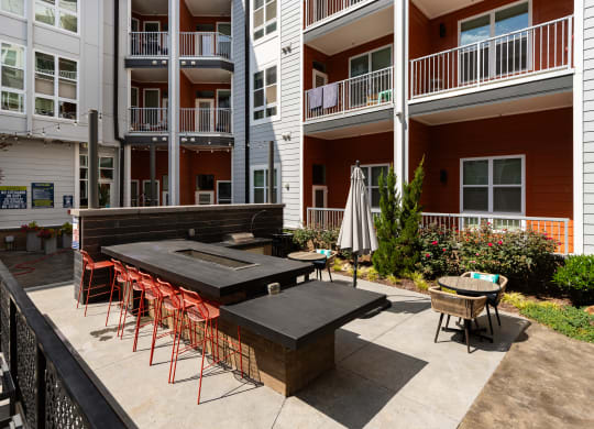 an outdoor patio with a firepit and tables and chairs in front of an apartment building  at Abberly Noda Vista Apartment Homes, Charlotte, NC, 28206