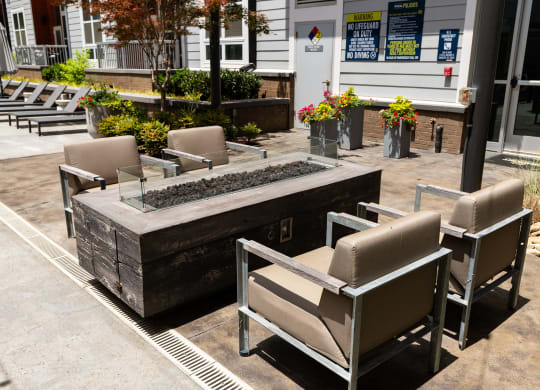 an outdoor seating area with chairs and a firepit in front of a building  at Abberly Noda Vista Apartment Homes, Charlotte