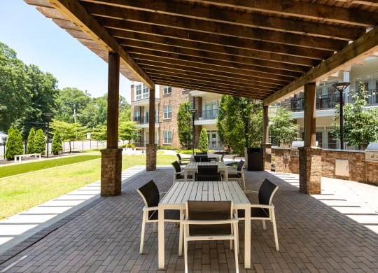 a patio with a wooden pergola and tables and chairs  at Abberly Onyx Apartment Homes, Georgia, 30033
