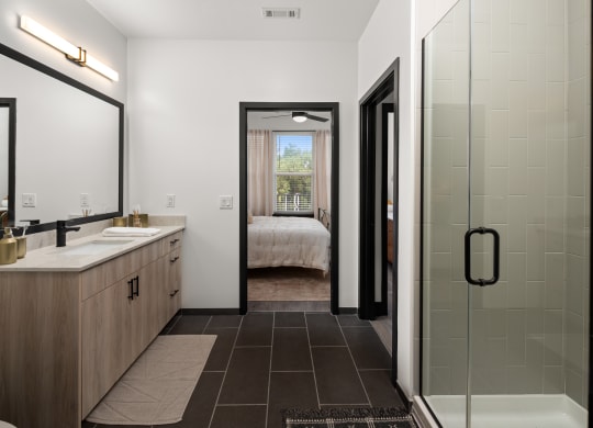 a bathroom with a glass shower stall and a double sink with a large mirror on the wall  at Abberly Riverwalk Apartment Homes, Nashville, Tennessee